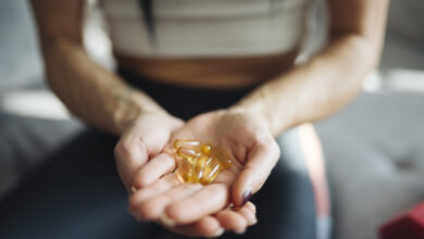 Hands holding golden capsules indoors during a wellness routine